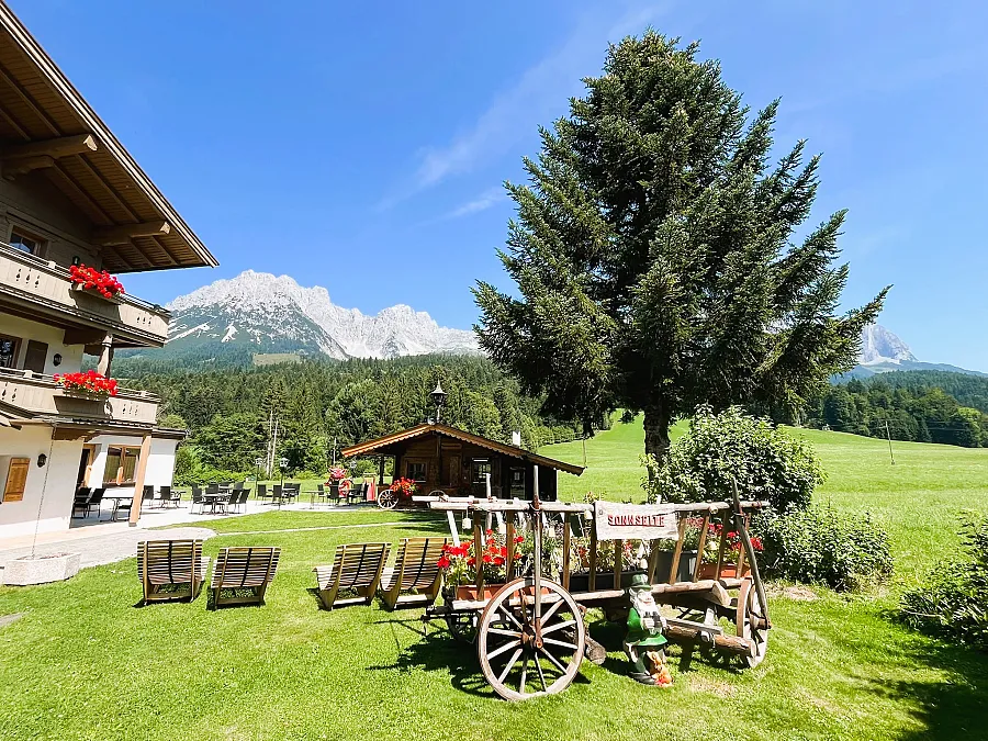 Liegewiese vor dem Landhaus mit Blumenwagen und Blick auf den Wilden Kaiser